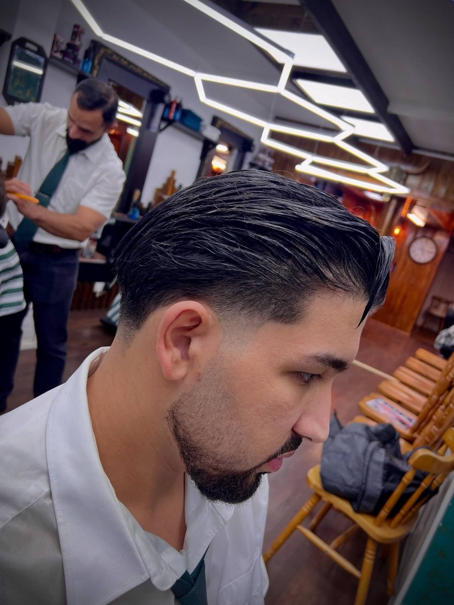 Barber finishing a slicked-back cut and beard